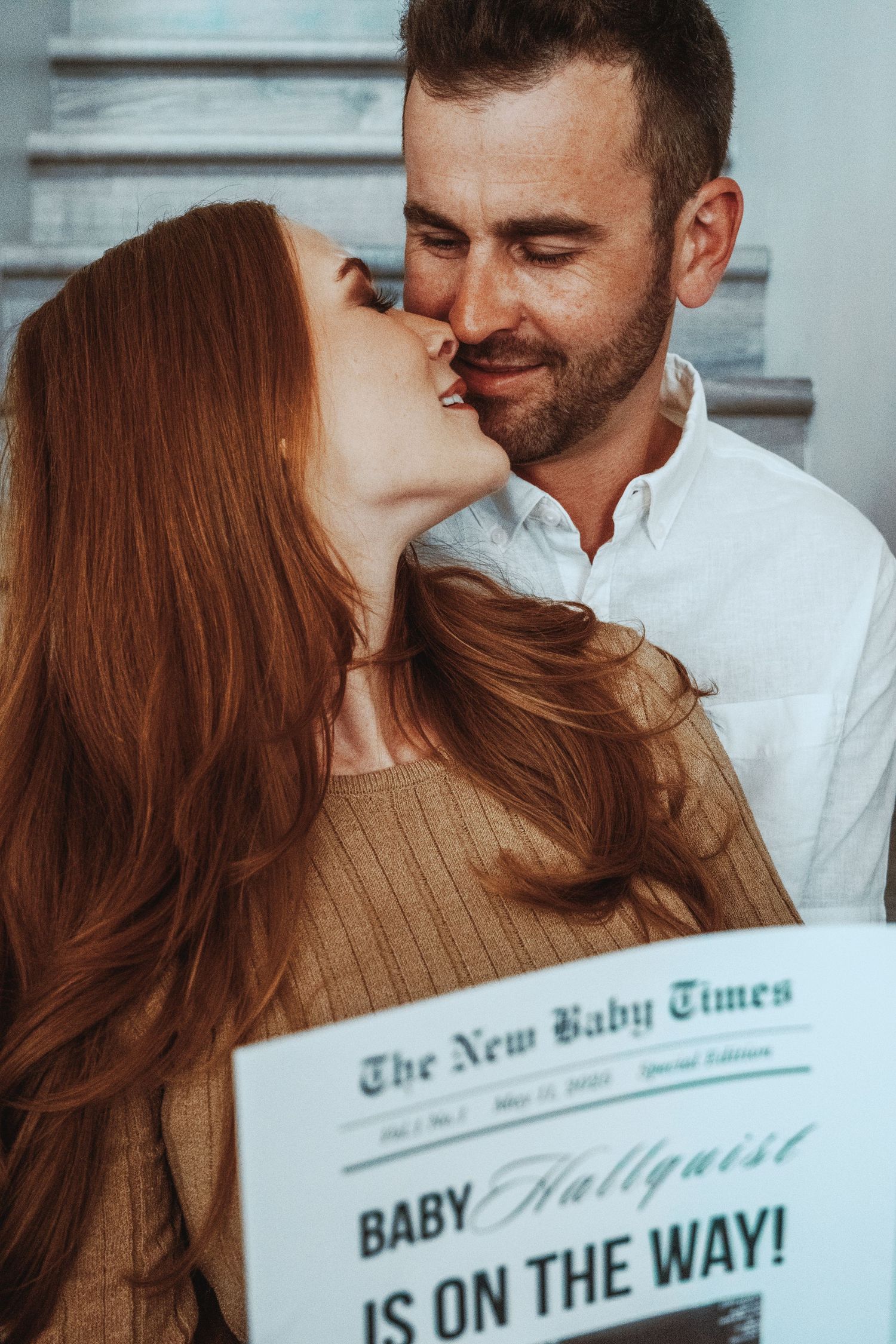 Couple poses with custom newspaper announcing their pregnancy news.