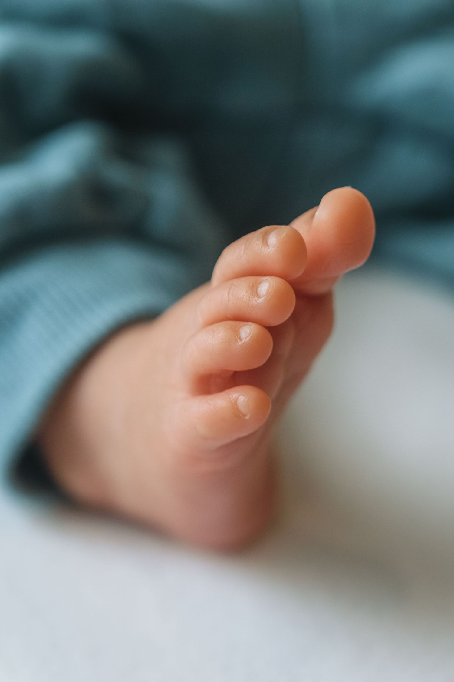 Close-up sequence of delicate baby toes against blue tinted background.