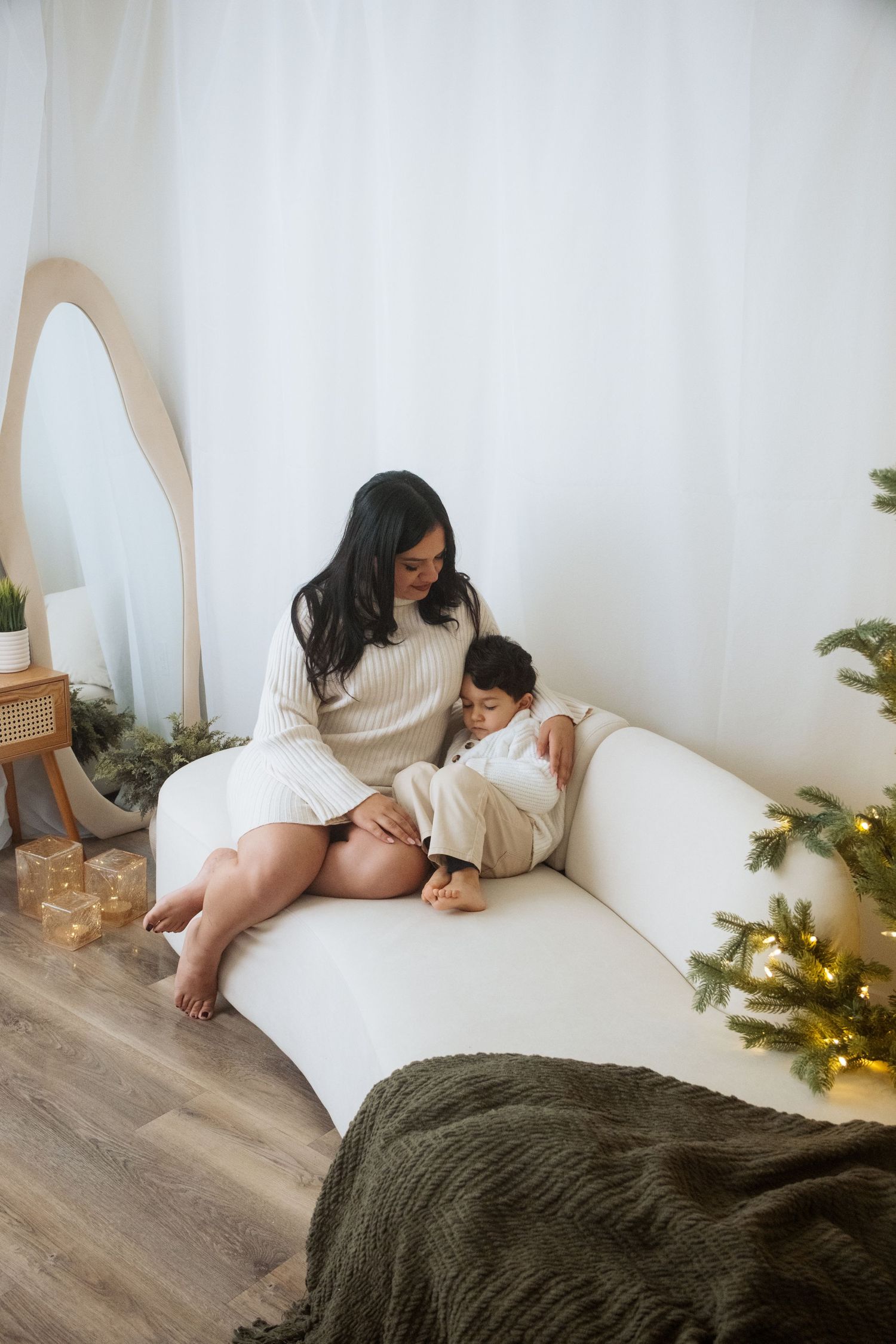 Cozy winter photoshoot on floor with white sweaters and Christmas decorations.