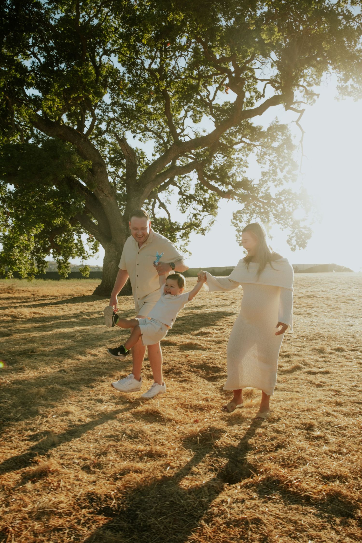 Family playing together on a sunlit hillside during golden hour.