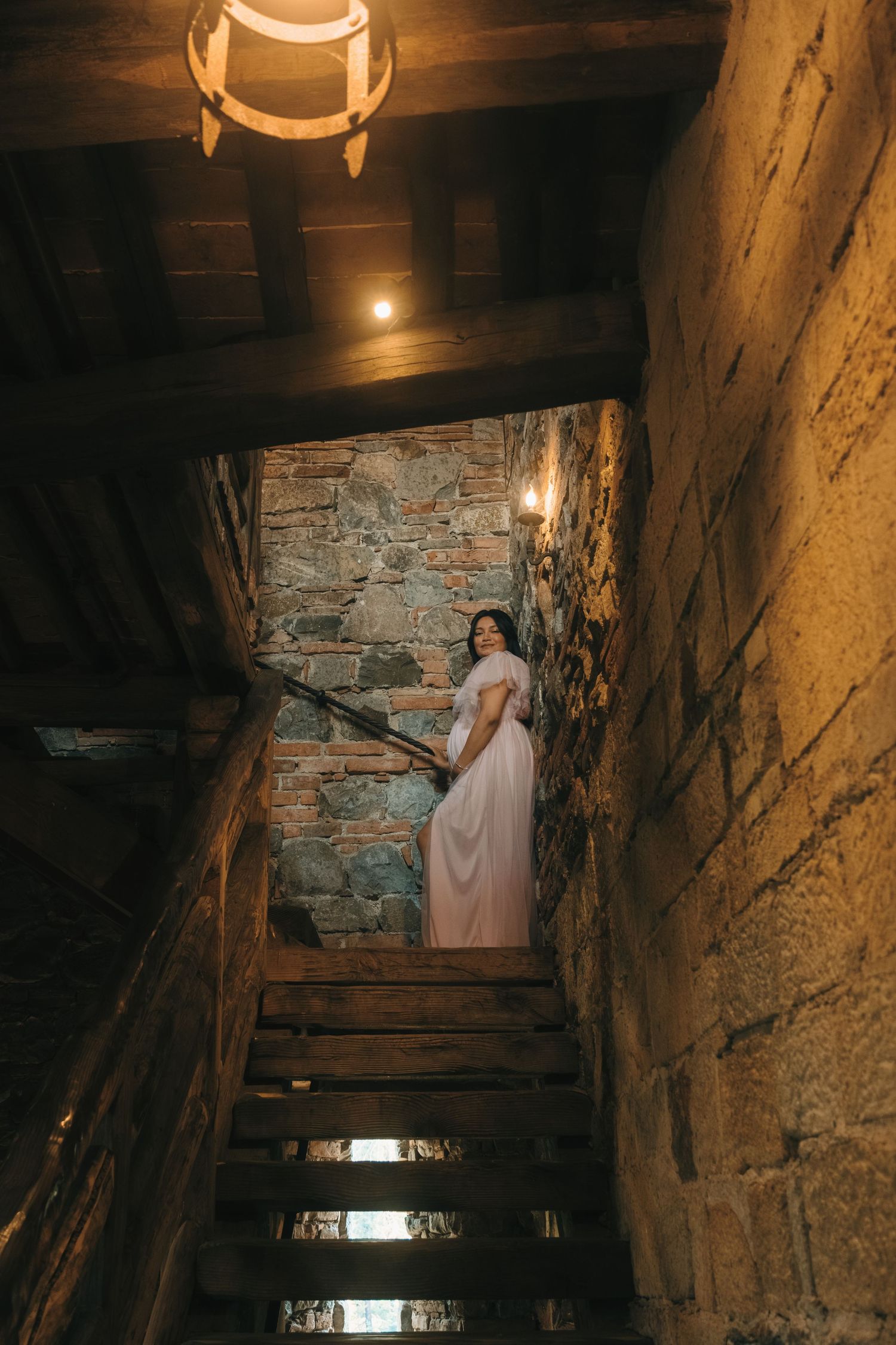 Atmospheric shot looking up stone stairs in a dimly lit castle interior.
