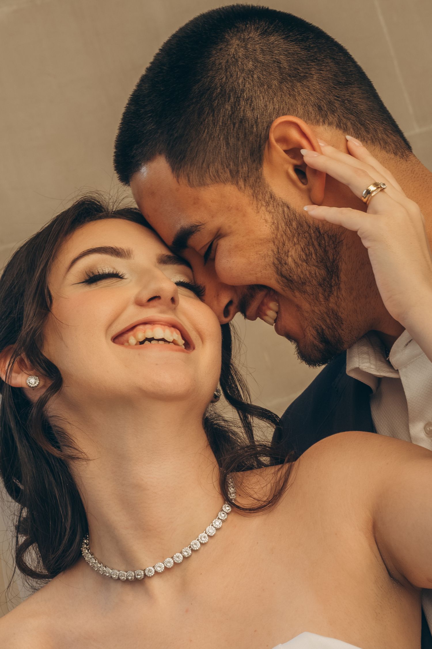A romantic couple shares an intimate moment with the woman wearing a pearl necklace and displaying joyful expressions.