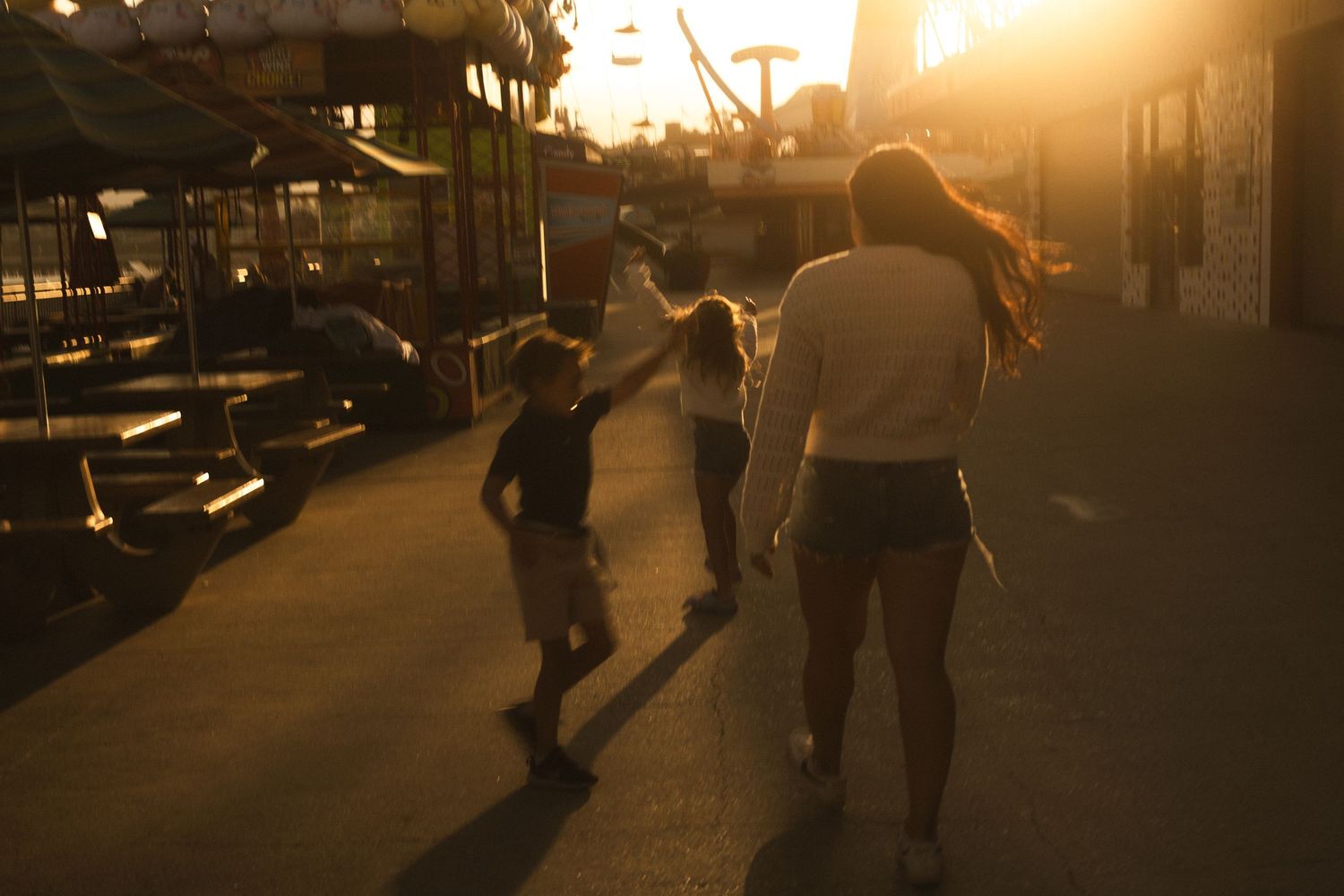 Family walking together on a sidewalk during golden hour sunset.