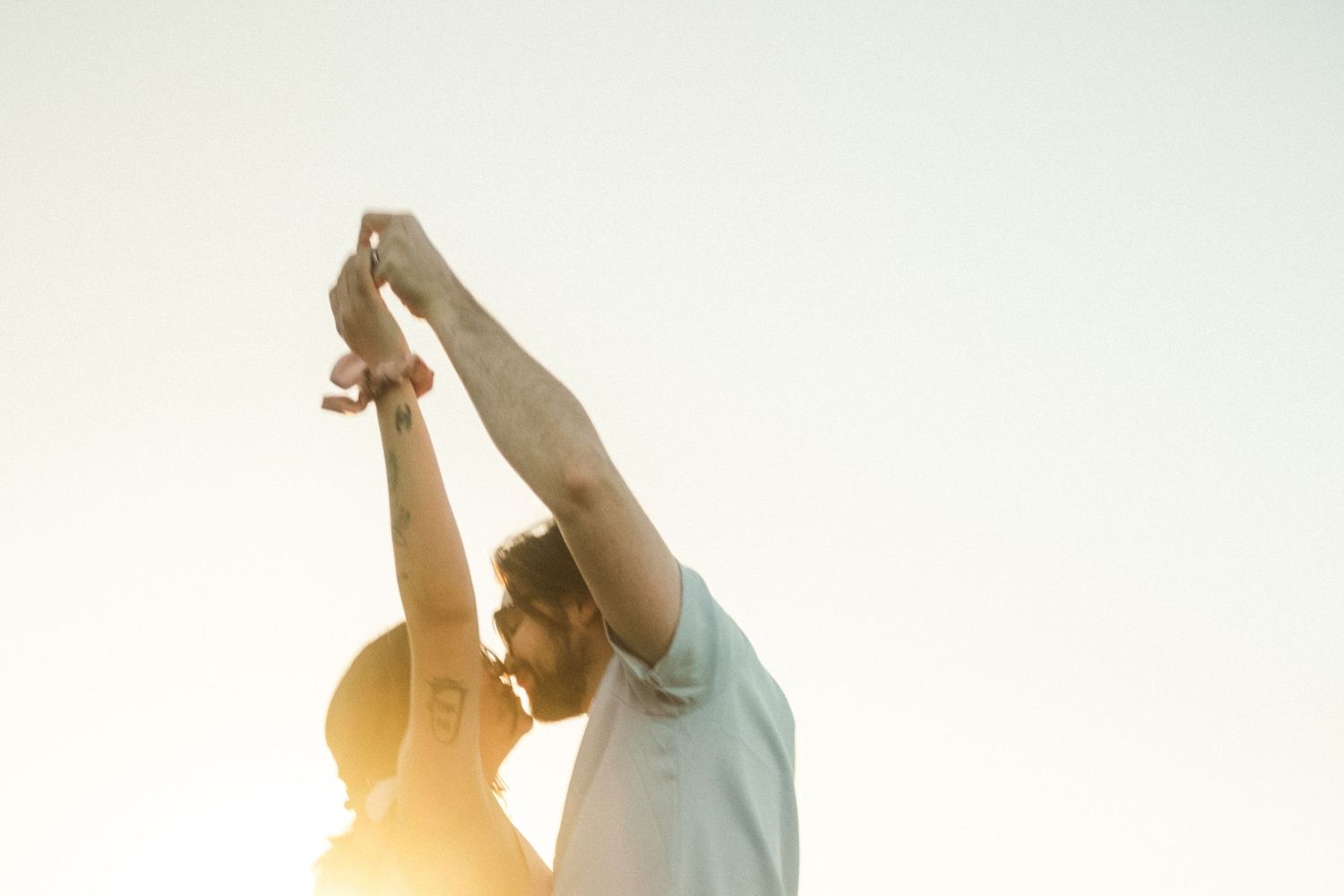 Dancing couple silhouetted against bright sunlight during sunset.