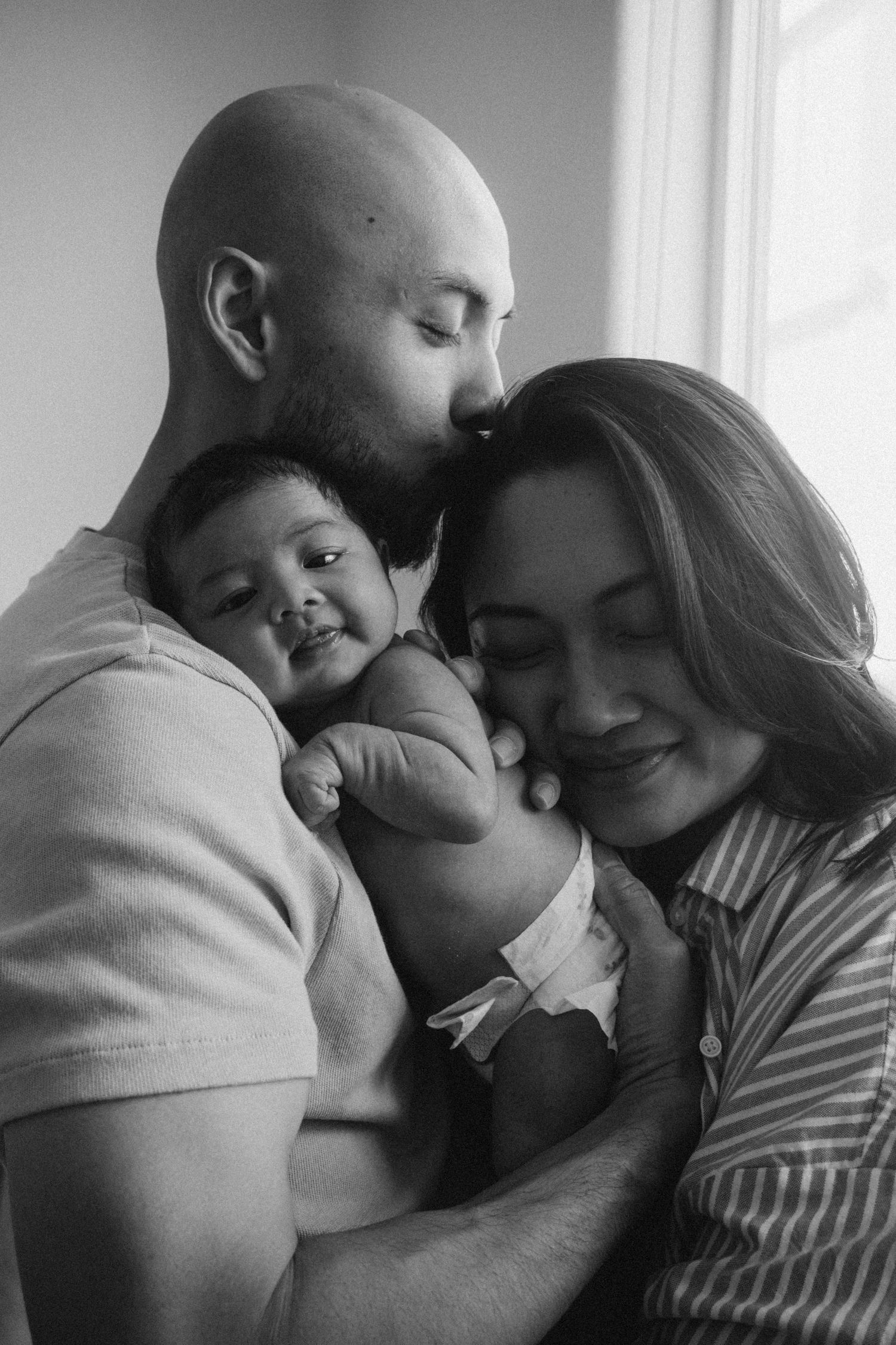 A series of black and white photos showing tender family moments between parents and baby in an intimate embrace.