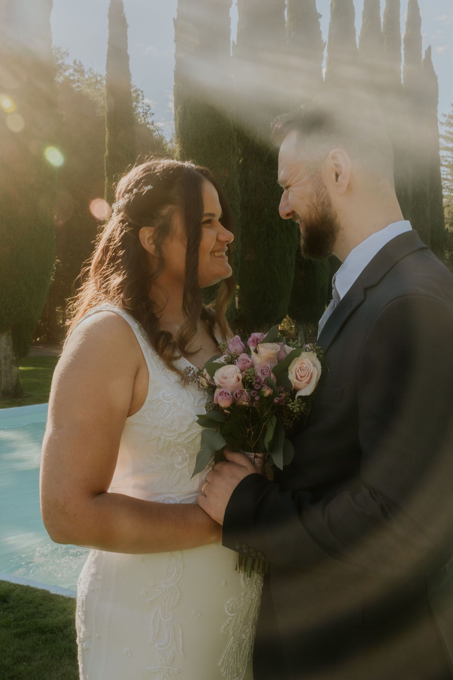 A couple shares an intimate moment in a garden setting with pink roses.