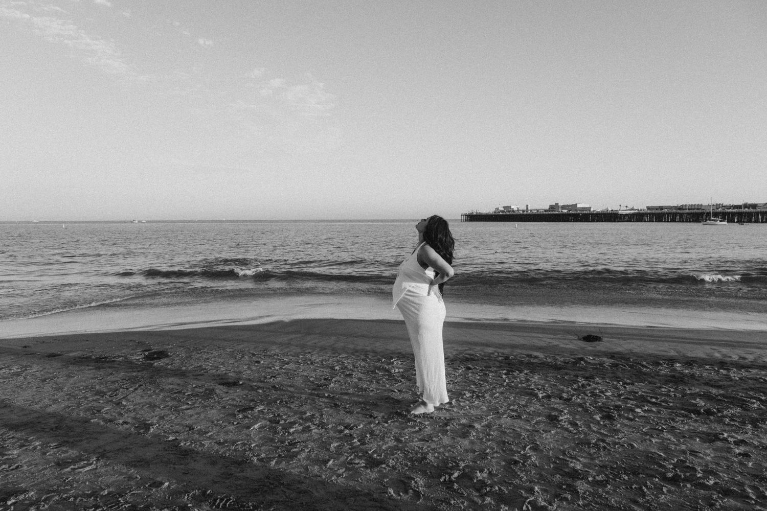 A serene black and white landscape of figures walking on a vast empty beach.