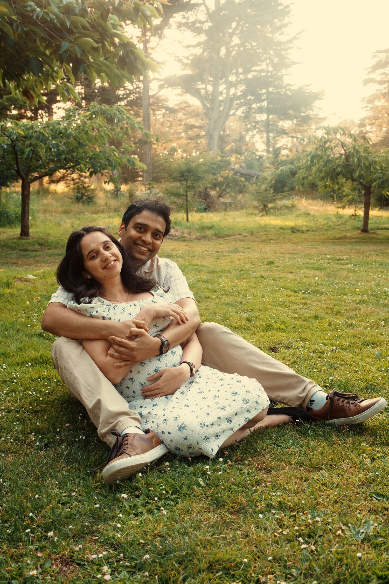 Couple relaxing together on grass during a sunny afternoon photoshoot.