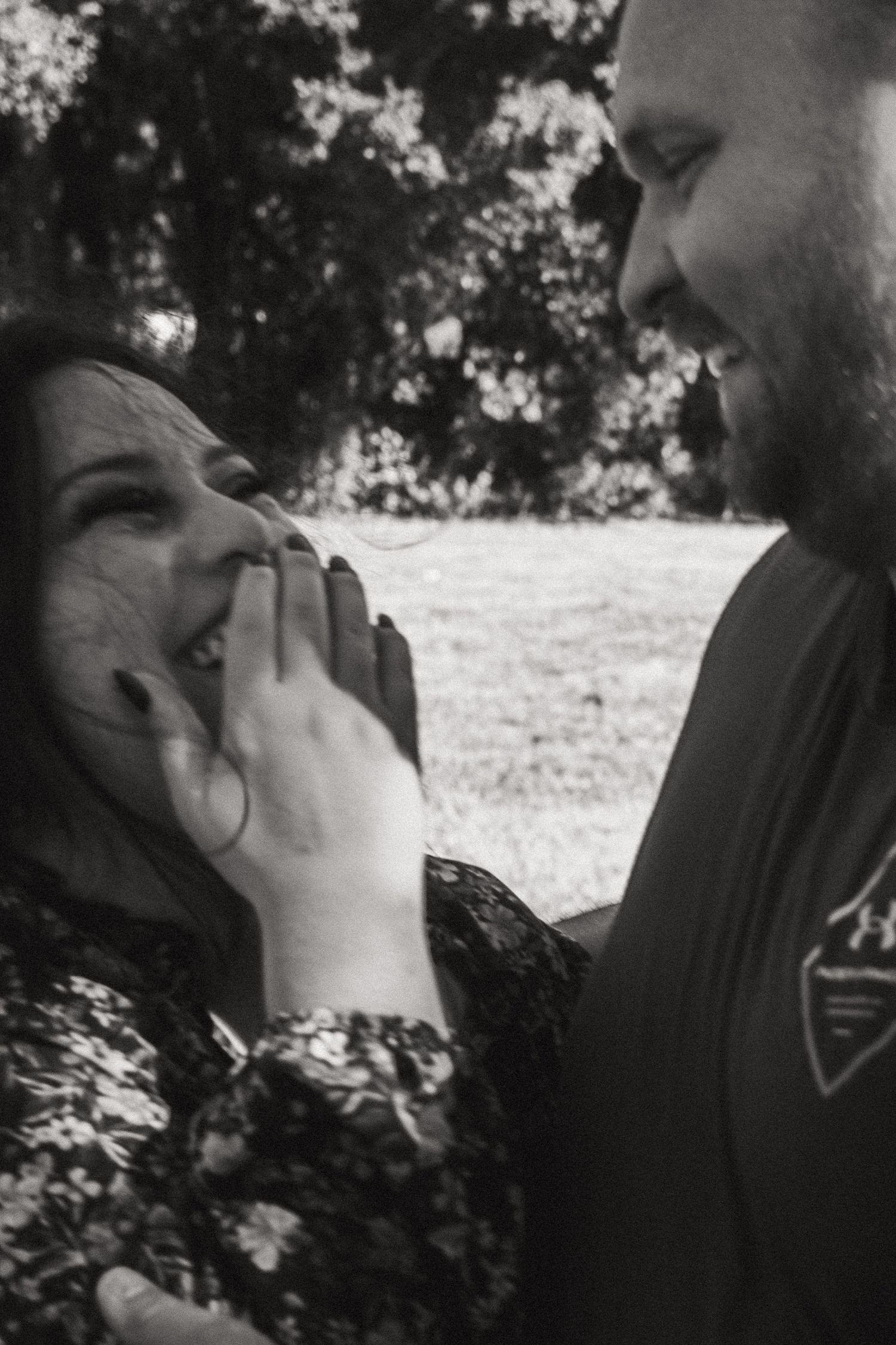 Black and white portrait capturing an intimate moment between a couple outdoors.