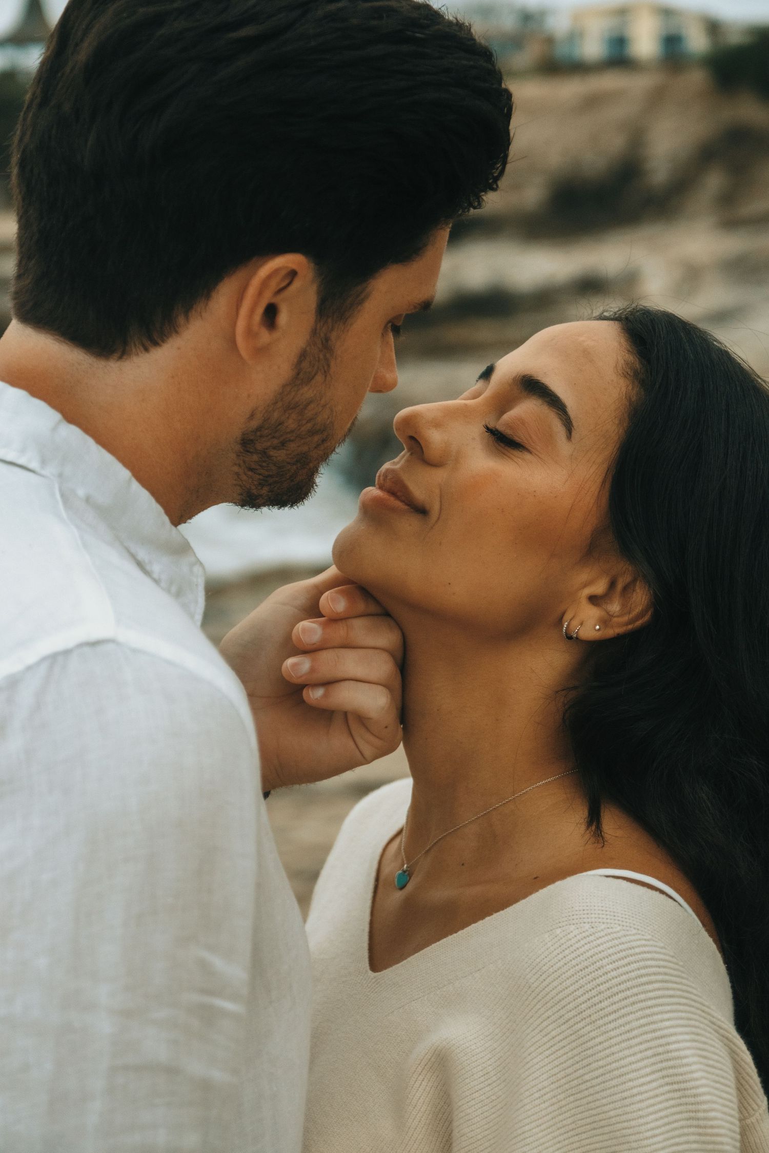 Romantic couple sharing tender moments during a beach photoshoot.