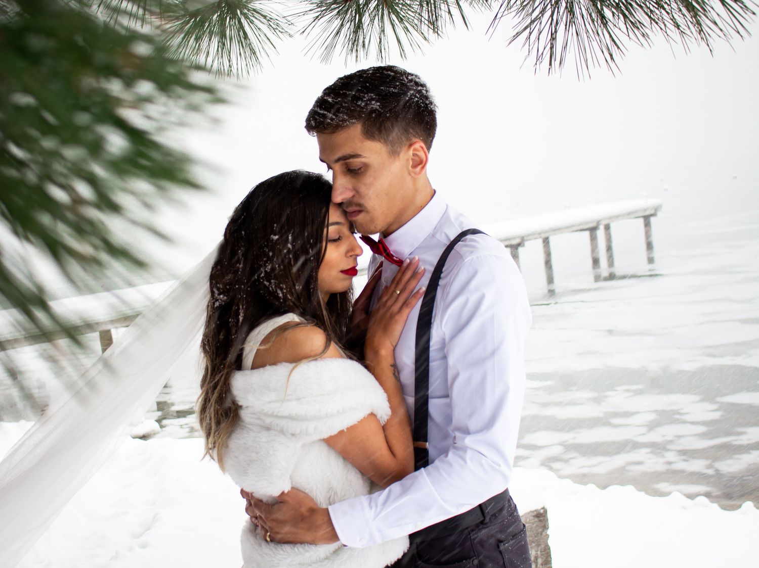 Romantic winter beach photoshoot with couple embracing in white dress and formal attire.