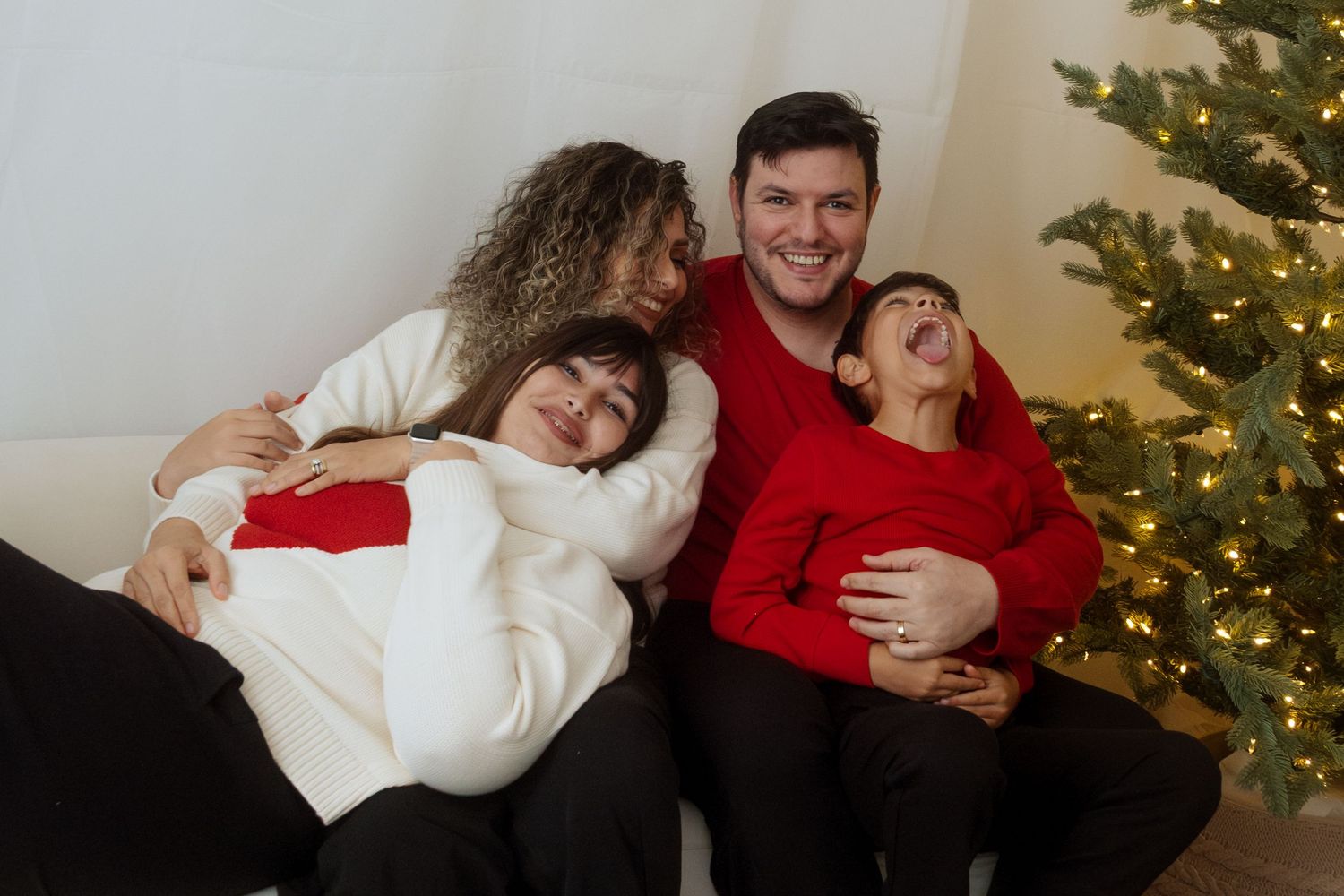 Festive couple photos with decorated Christmas tree and warm sweaters.
