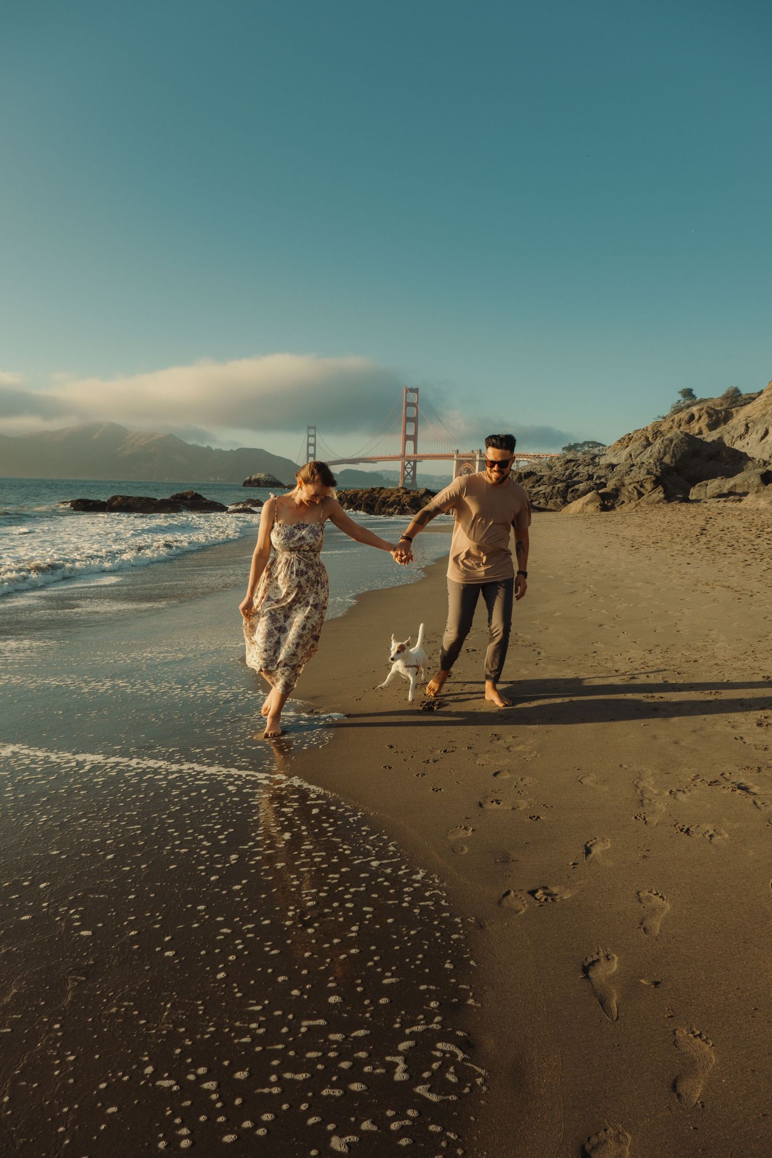 Family playing and running together on beach with Golden Gate Bridge visible in background.