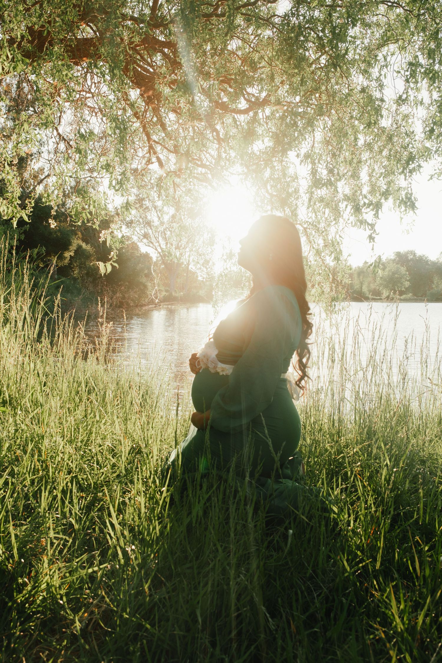 Silhouetted couple embracing in tall grass during golden sunset.