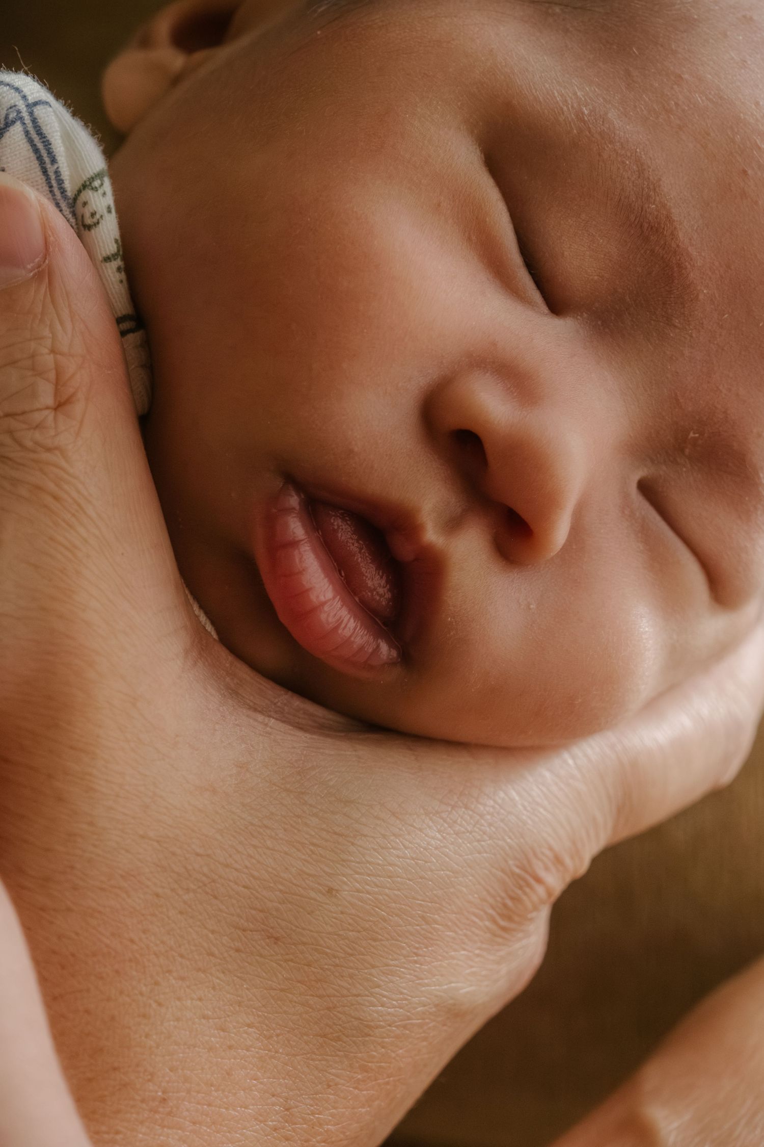 Artistic close-up of baby's lips and nose in warm lighting.