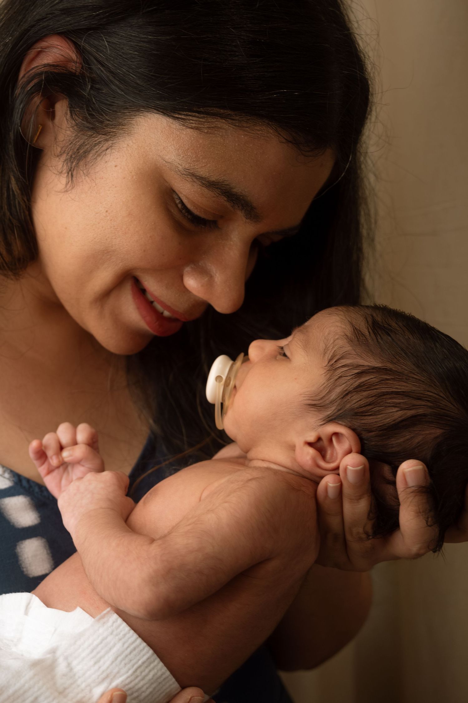 Tender moments between parent and newborn in warm lighting.