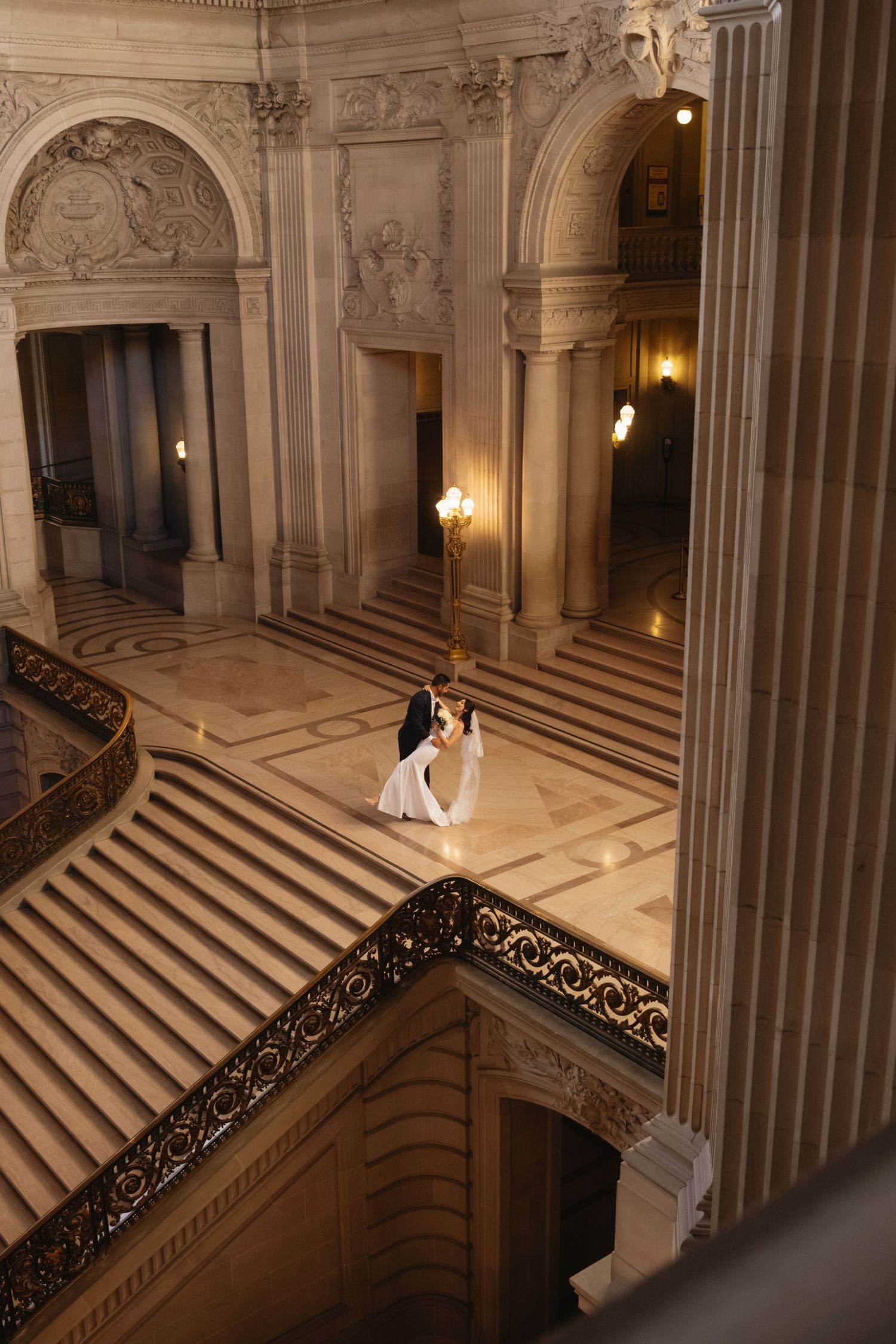 Elegant grand staircase in a historic building with ornate marble columns and decorative railings.