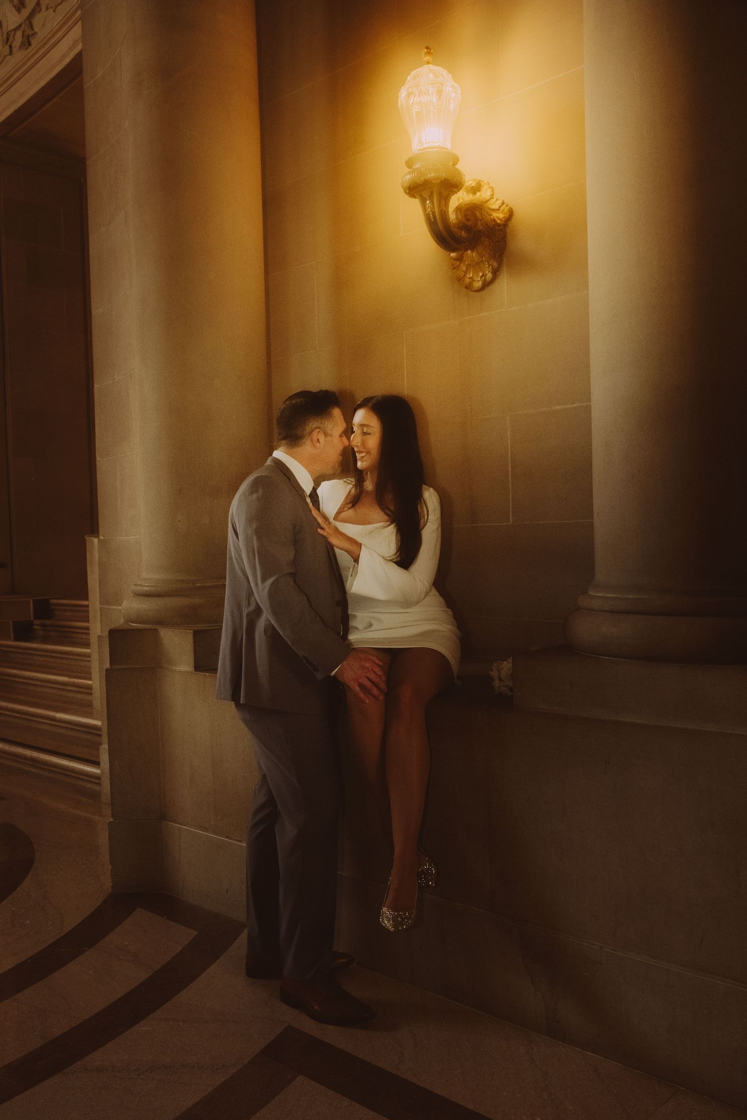 Romantic embrace in dimly lit corridor with classical columns.