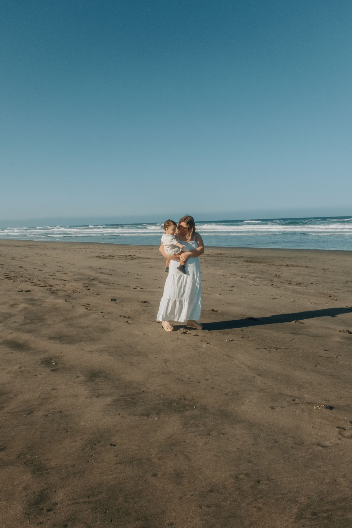 A sequence of tender interactions between two figures on a sandy beach with ocean waves in the background.