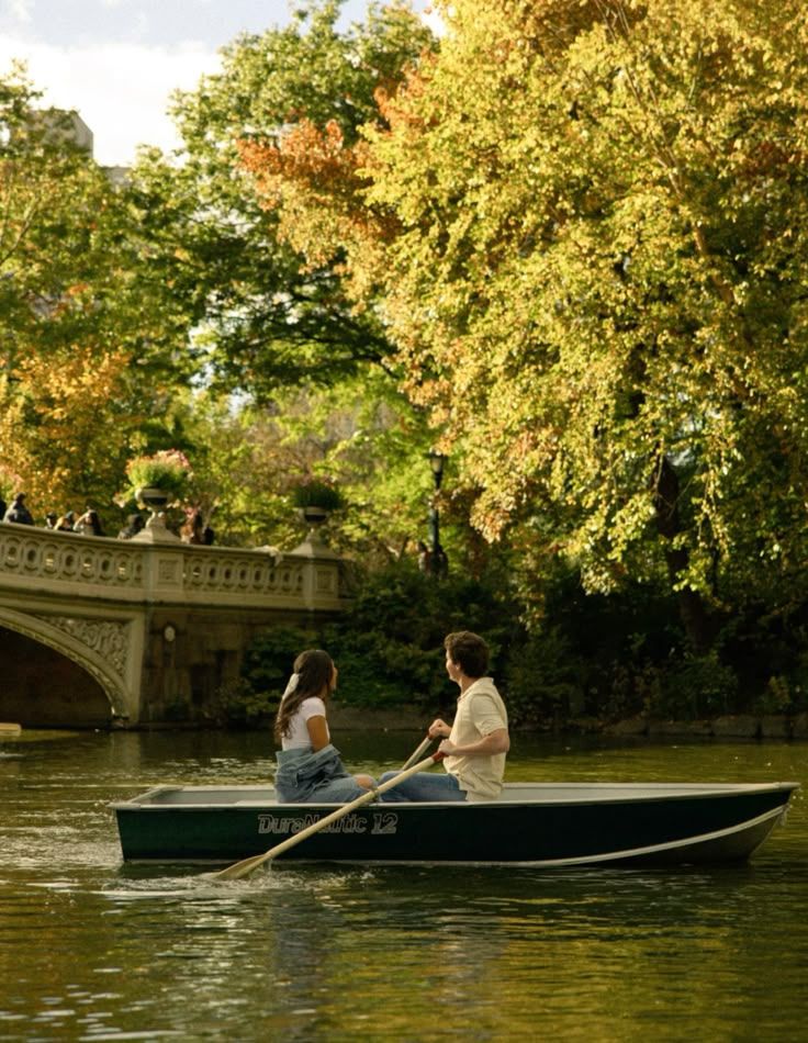 Rowboats gliding past autumn trees along Central Park lake in golden light.