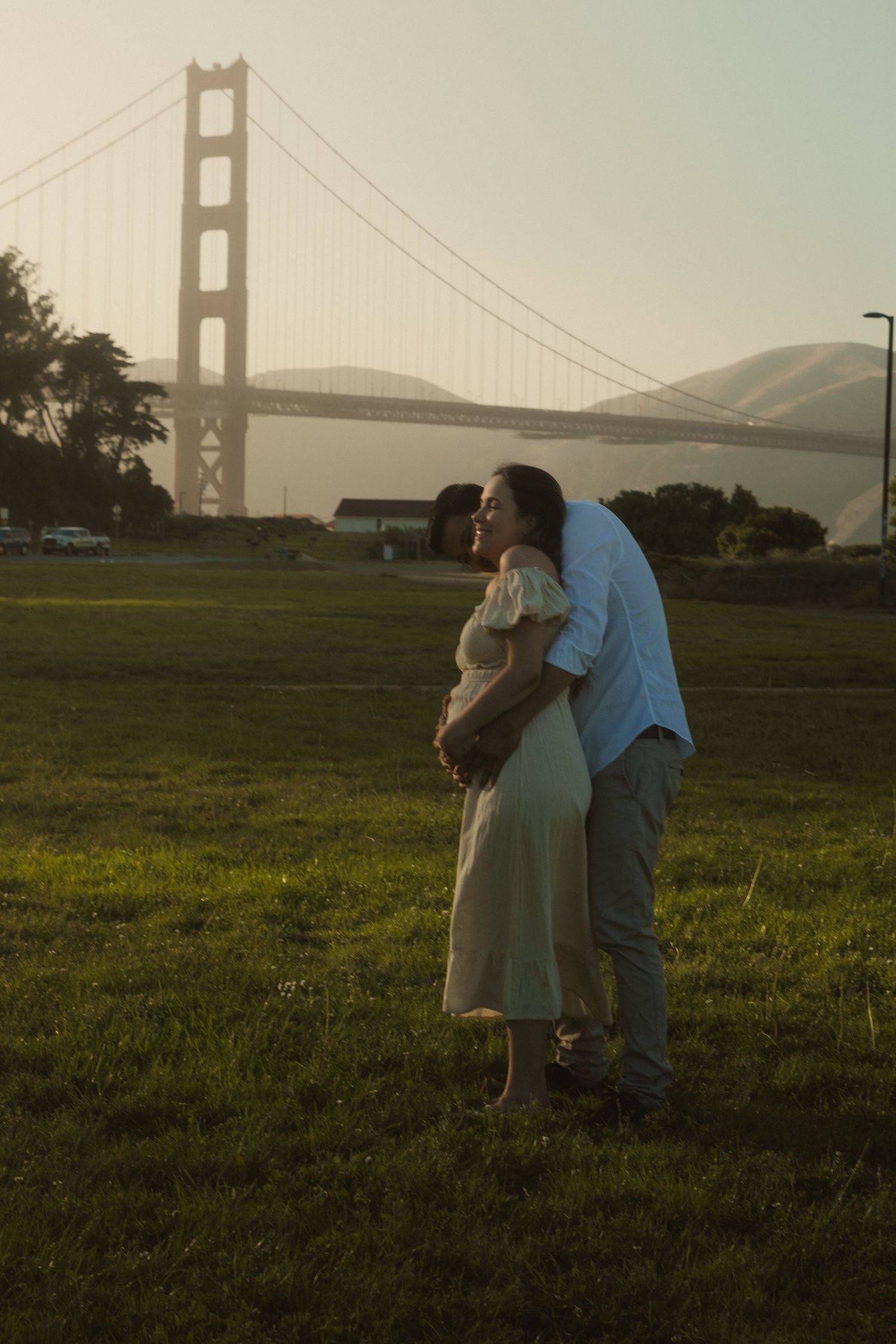 People enjoying a moment together in a field with the Golden Gate Bridge in the distance.