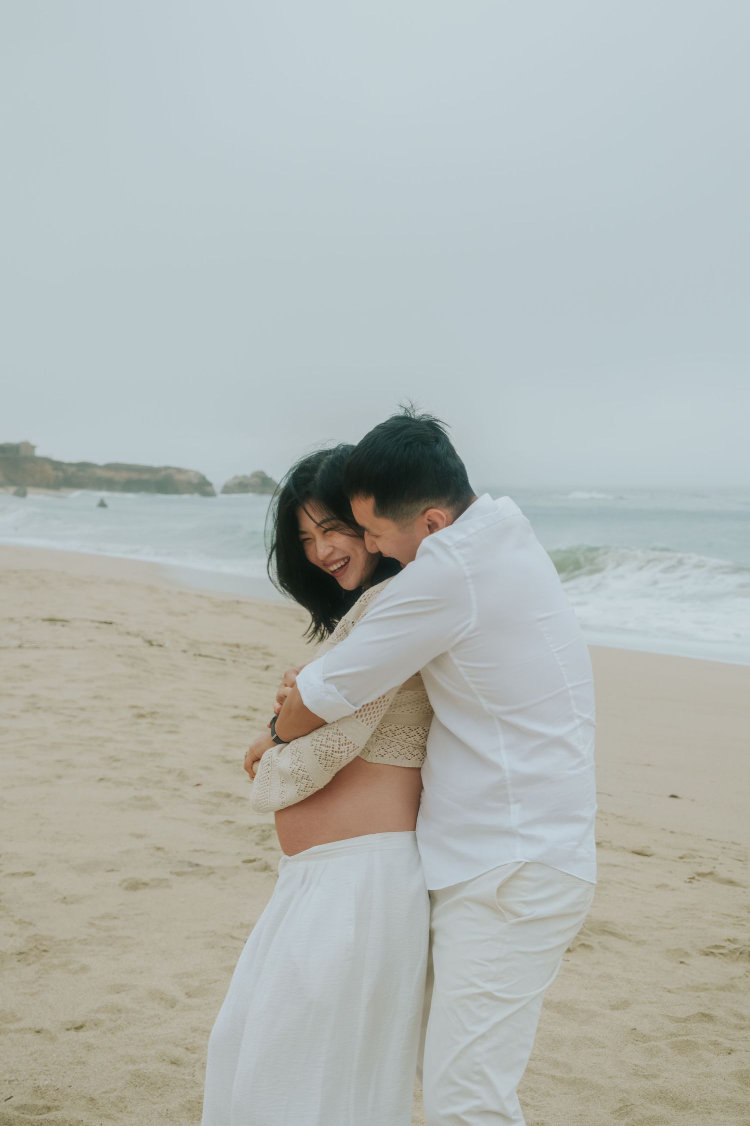 Intimate beach photography session showing tender moments between a couple in white outfits.