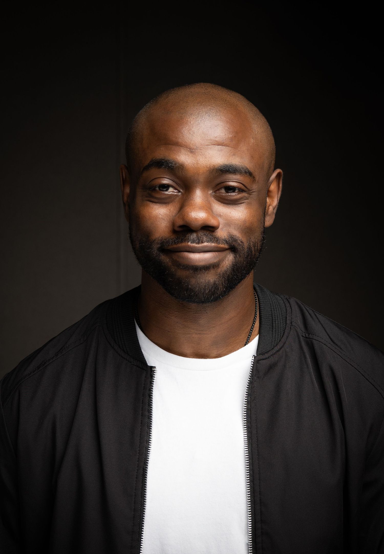 A series of black and white portraits showing a person wearing a black jacket and white t-shirt against a dark background.