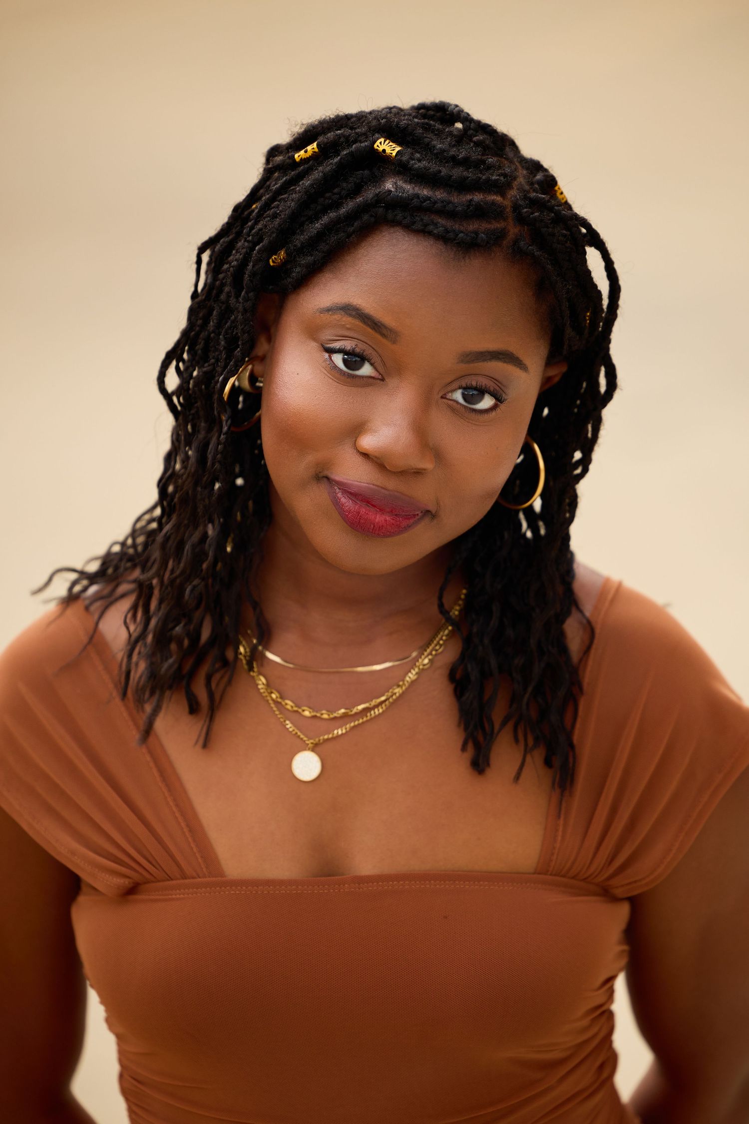 Portrait series showing a person in a brown top with dreadlocks and gold jewelry against a beige background.