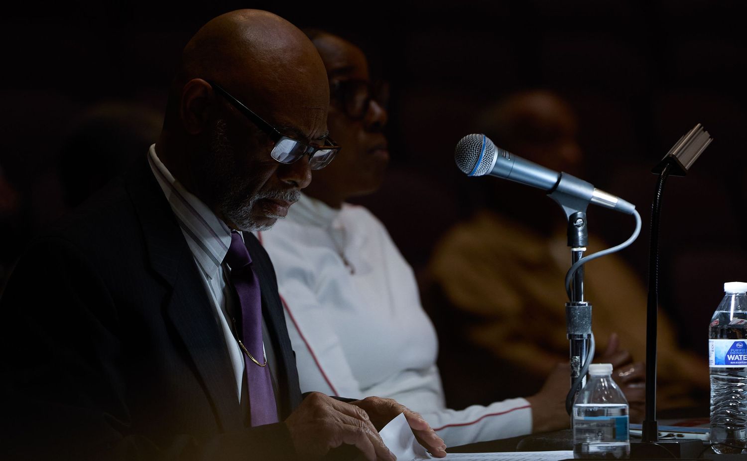 Professional speakers sit at a conference table with microphones during a panel discussion event.