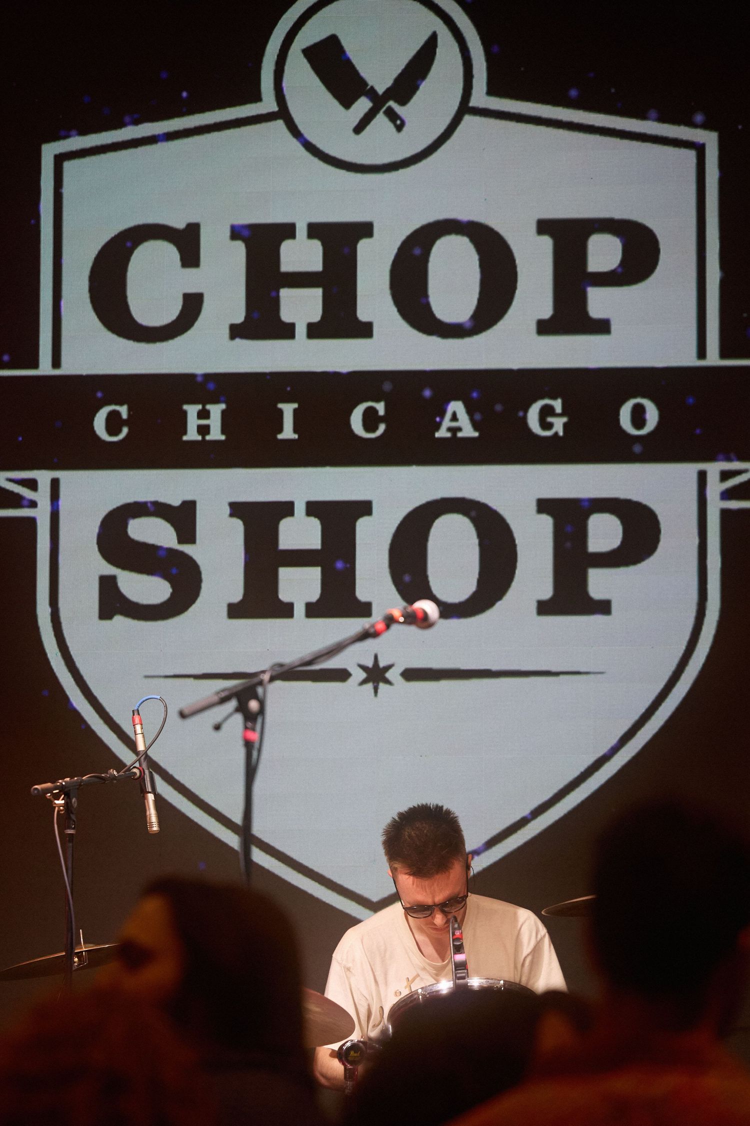 A dimly lit stage with illuminated signage displaying 'CHOP SHOP' in white letters against a dark background.