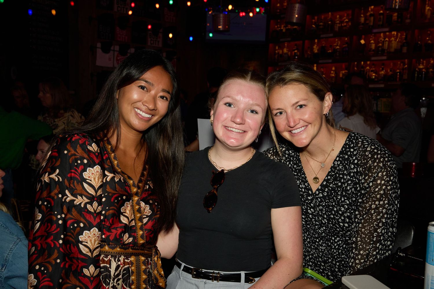Group of friends enjoying drinks and socializing at a dimly lit bar or restaurant.