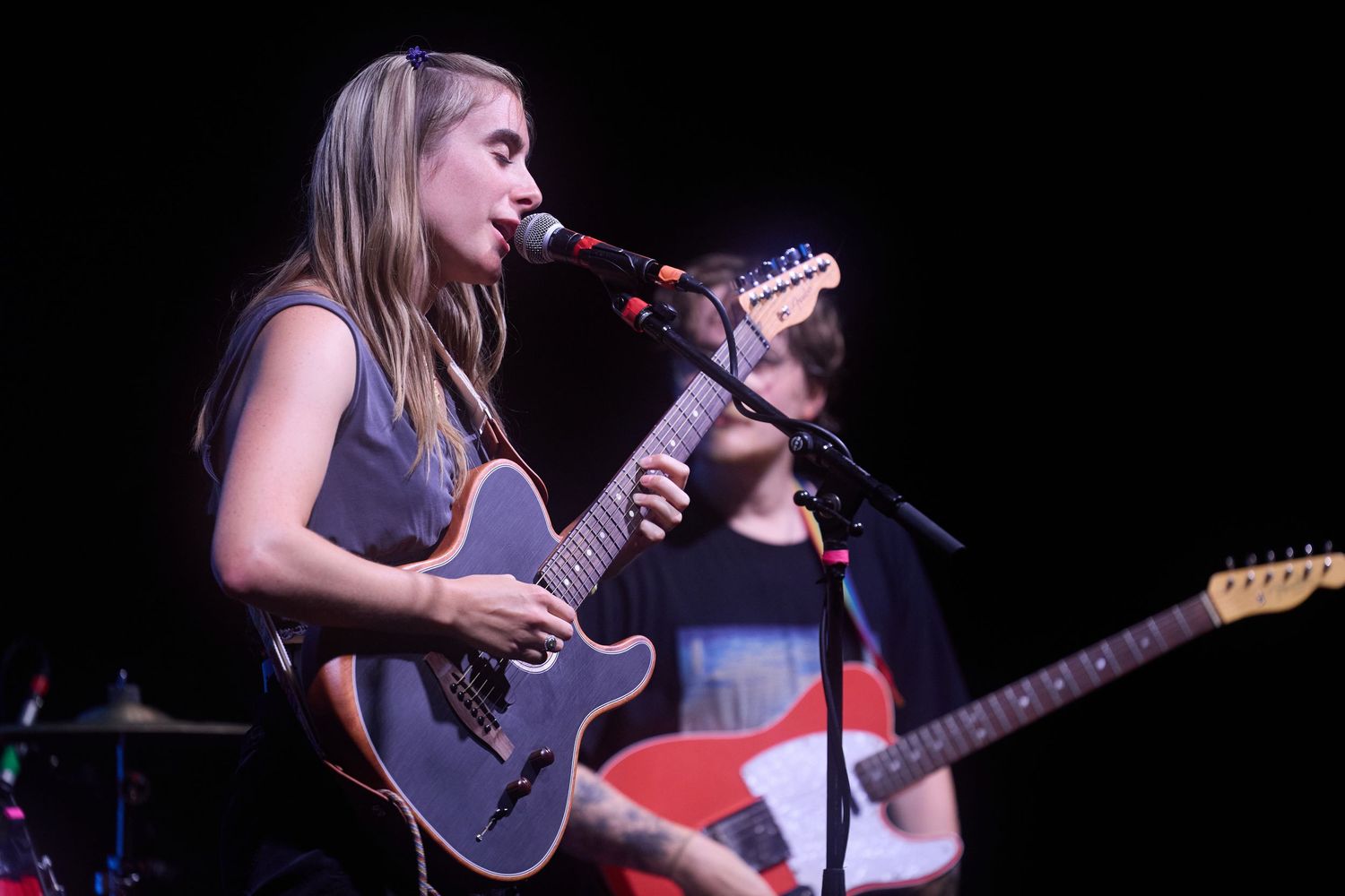 Musicians perform on stage with guitars and microphones during a live concert performance.