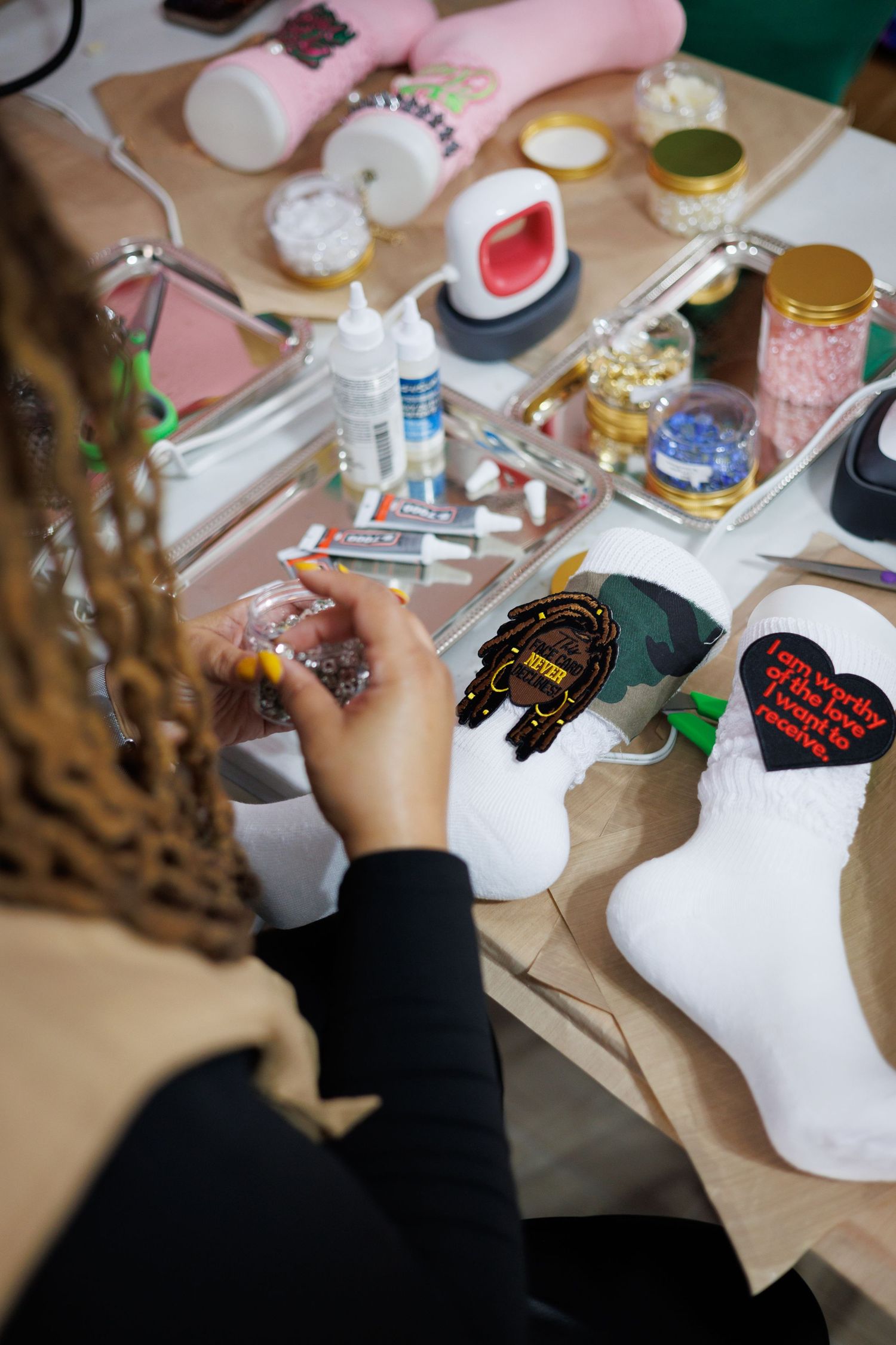Artist painting details on a white carnival mask with colorful paints and brushes on a craft table.