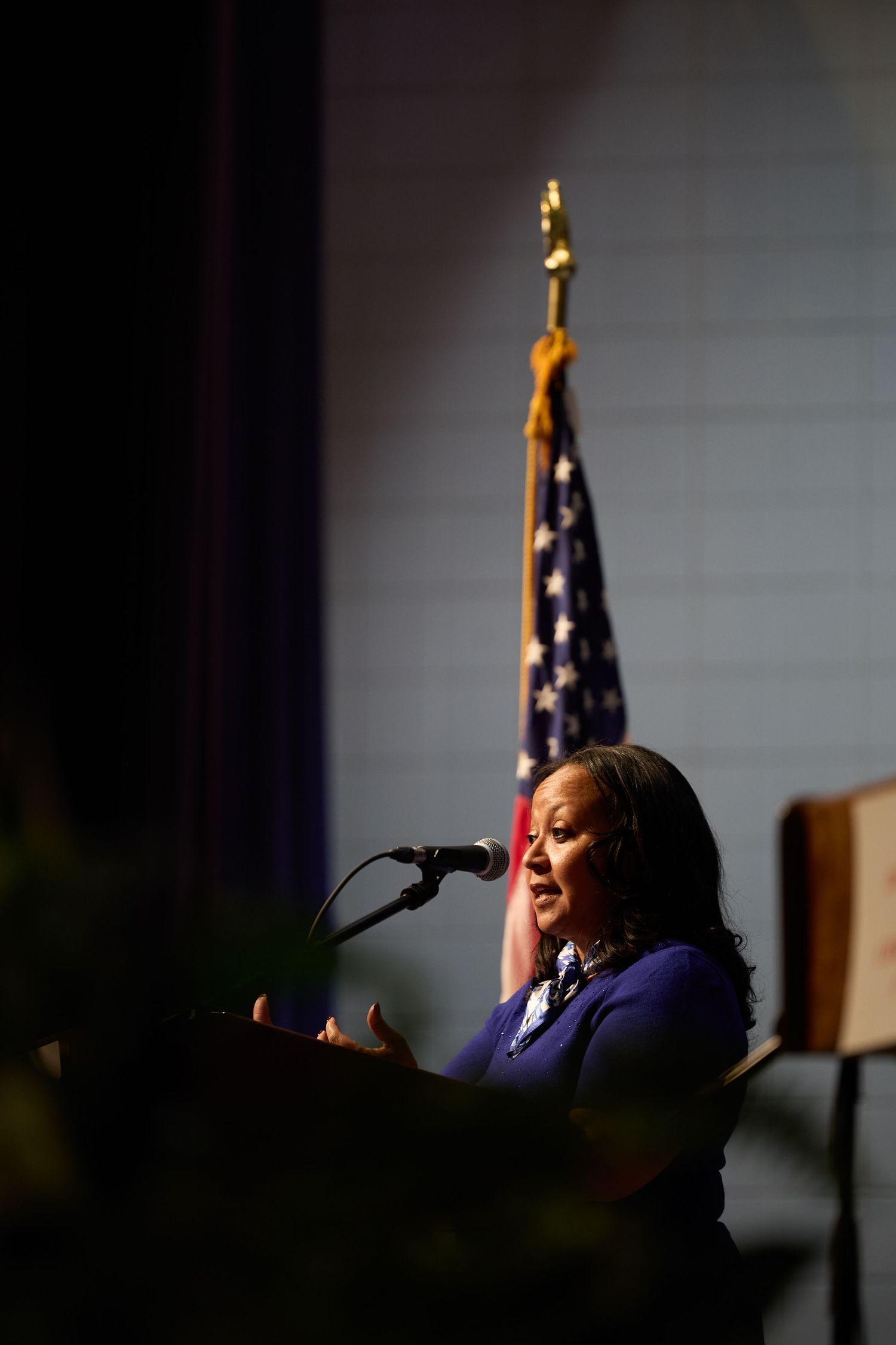 Speaker stands at podium with American flag in background during official government event.