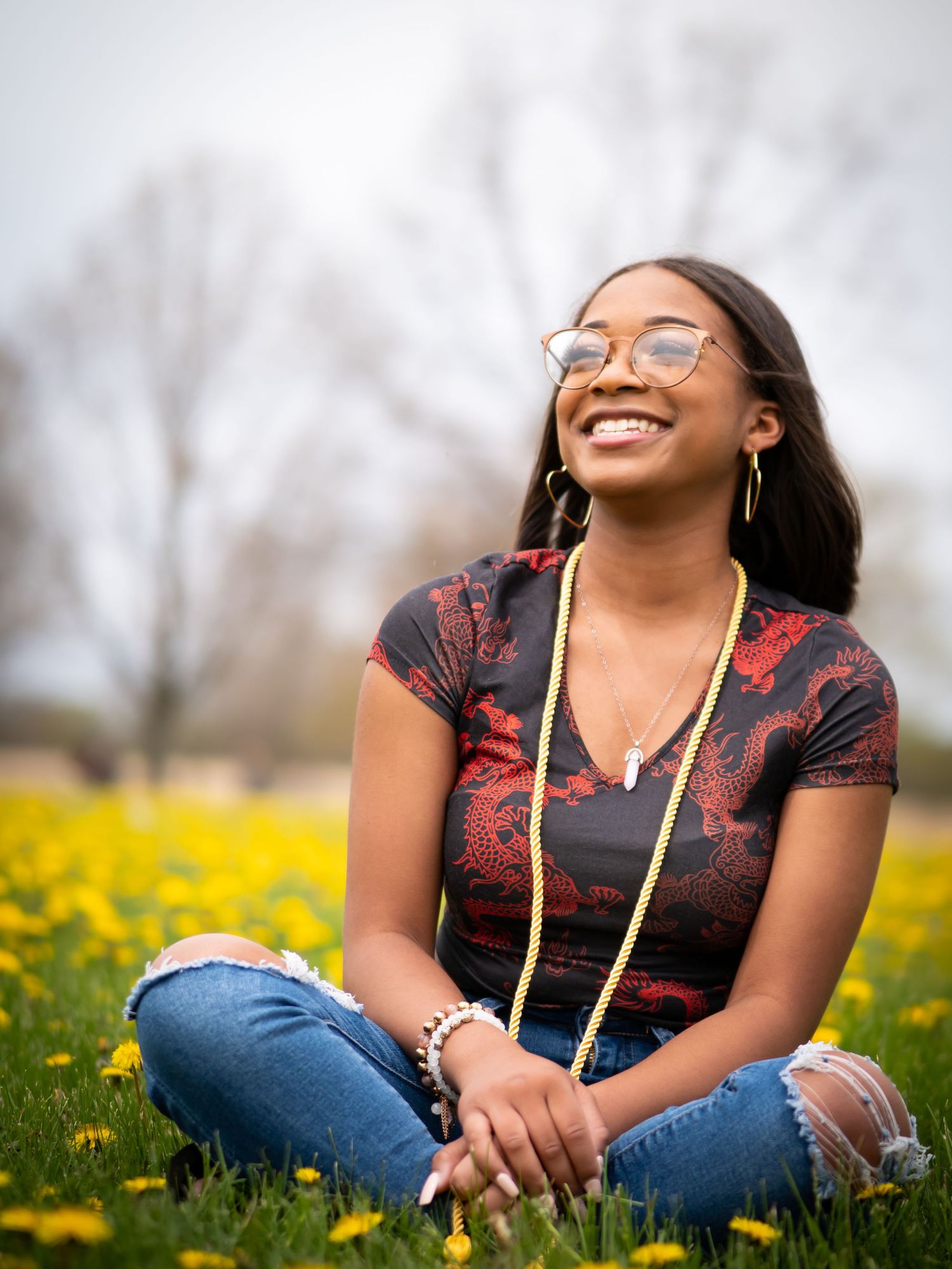 Person wearing a black top with red accents sits in a field of yellow wildflowers on a spring day.