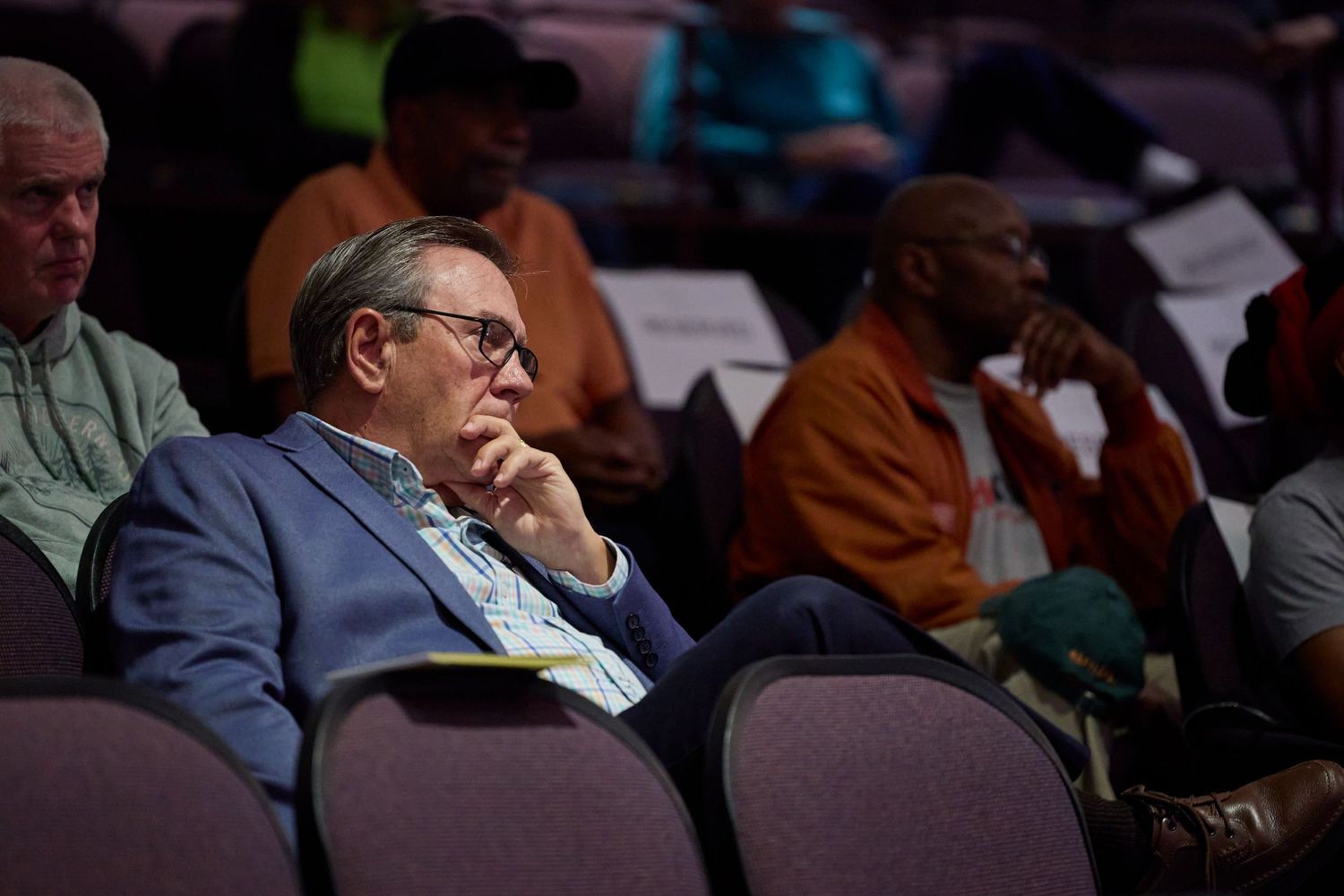 Audience members sit in rows of theater seats during what appears to be a conference or presentation.