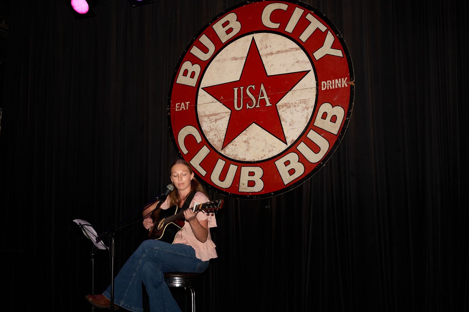 A collection of vintage red and white circular 'Bub City Club City' logos and signs displayed against a dark background with girl guitar.