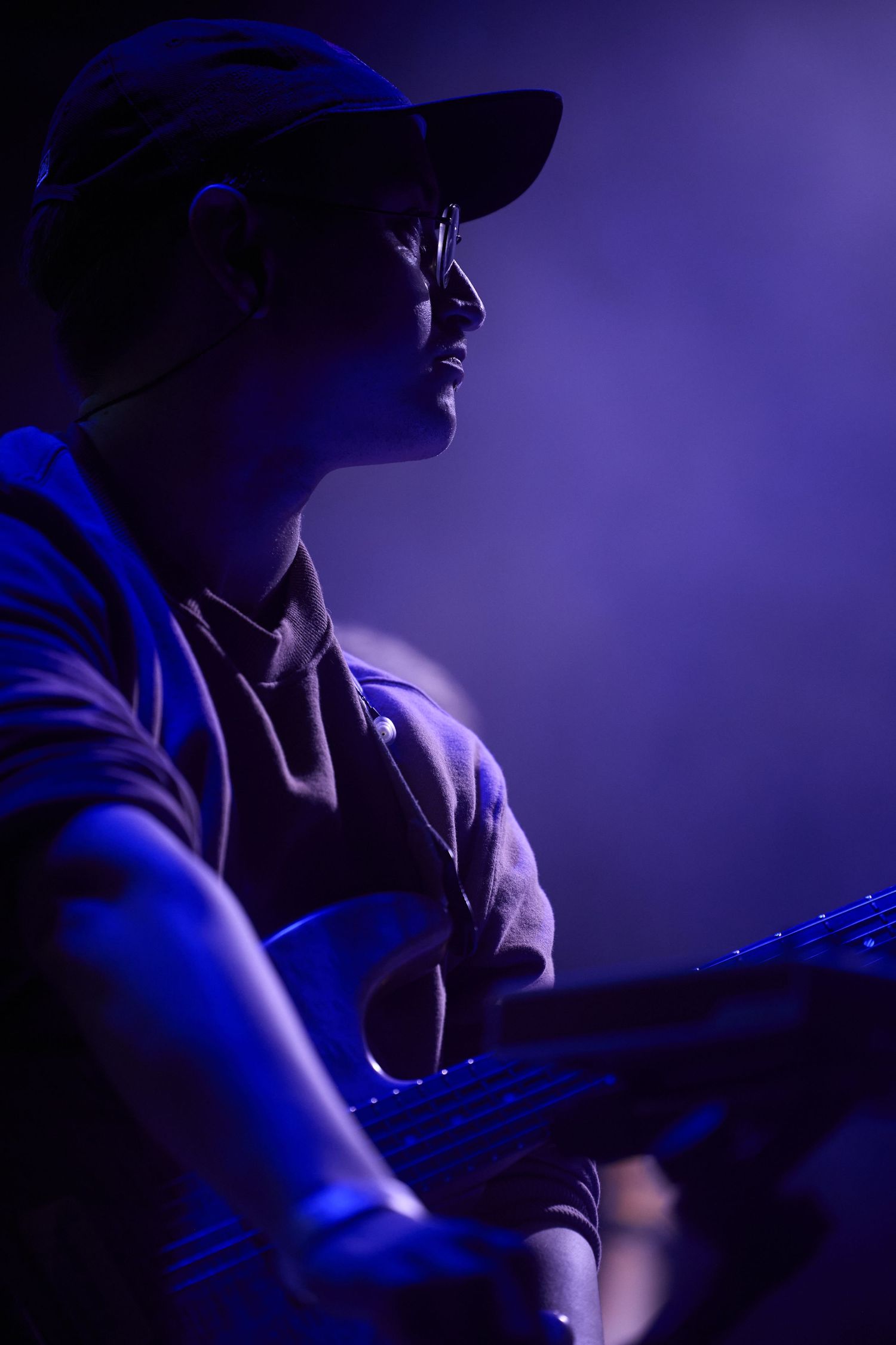 A musician performs in silhouette against a deep purple stage lighting background.