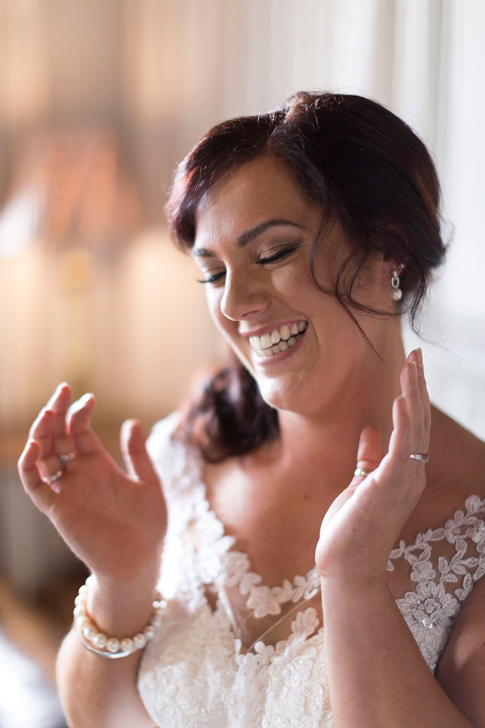 Colour bridal portrait of bride smiling with the bridesmaids before the ceremony. Photo by Raymond Mather.