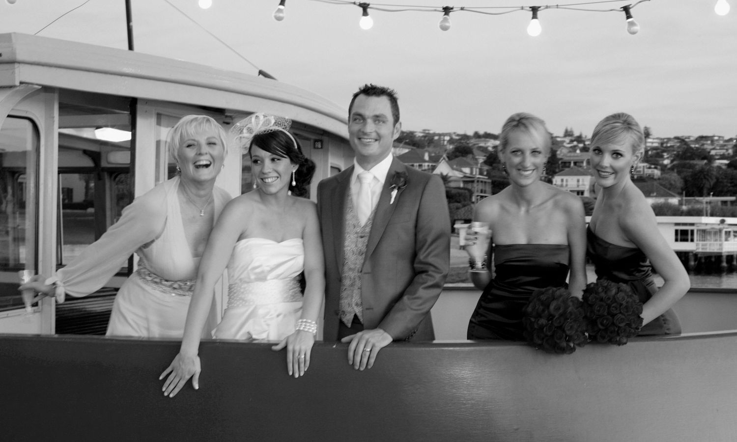 Monochrome group portrait on a terrace capturing timeless elegance and laughter of the bridal party. Photo by Raymond Mather.