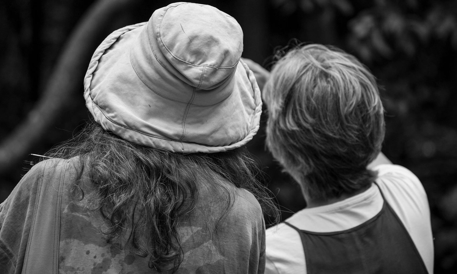 Black and white candid photo of two women talking closely during an outdoor art workshop. Photo by Raymond Mather.