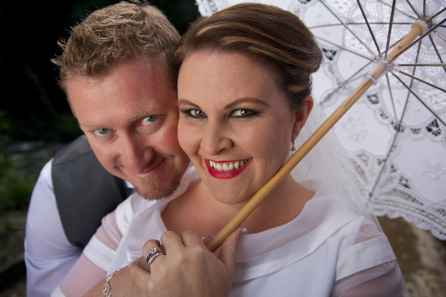Couple portrait beneath an umbrella, classic romance and quiet delight. Photo by Raymond Mather.