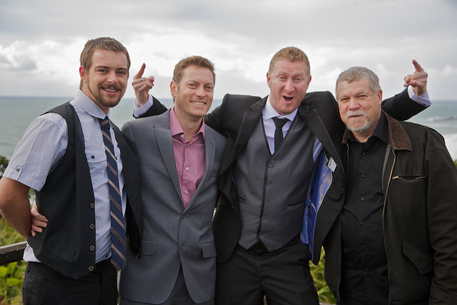 Colour candid of groomsmen laughing together outdoors after the ceremony. Photo by Raymond Mather.