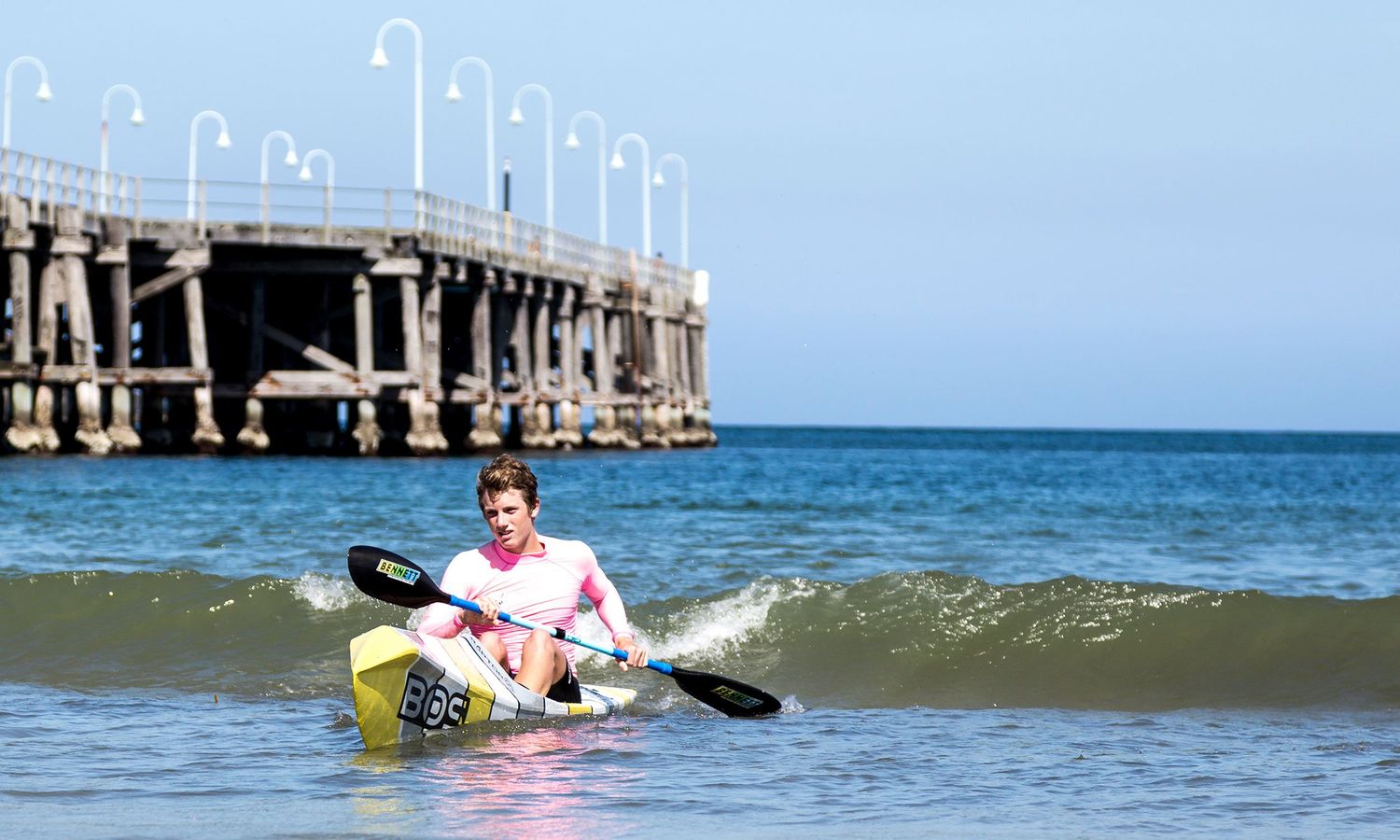 Colour action photograph of kayaker coming ashore, Coffs Harbour Jetty, representing vitality and healthy living. Photo by Raymond Mather.