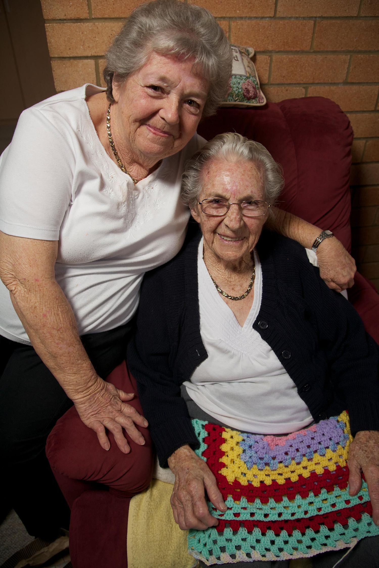 Colour portrait showing the connection between two elderly women, their bond expressed through touch and laughter. Photo by Raymond Mather.