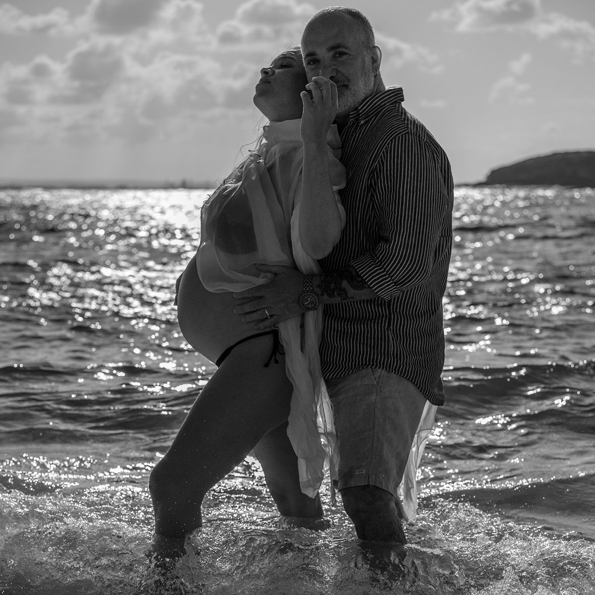 Black and white candid photo of couple laughing together in the shallows at sunset. Photo by Raymond Mather.