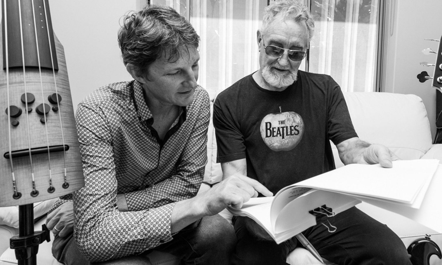Monochrome candid portrait of two writers sharing ideas over a manuscript at home. Photo by Raymond Mather.
