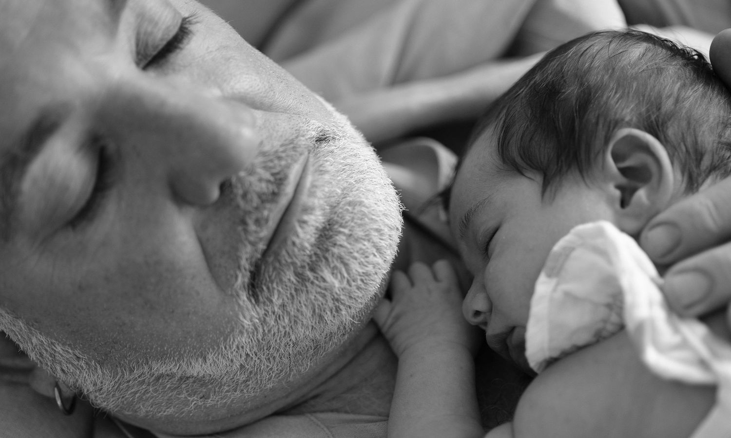 Father and baby resting together, peace in pure connection. Photo by Raymond Mather.