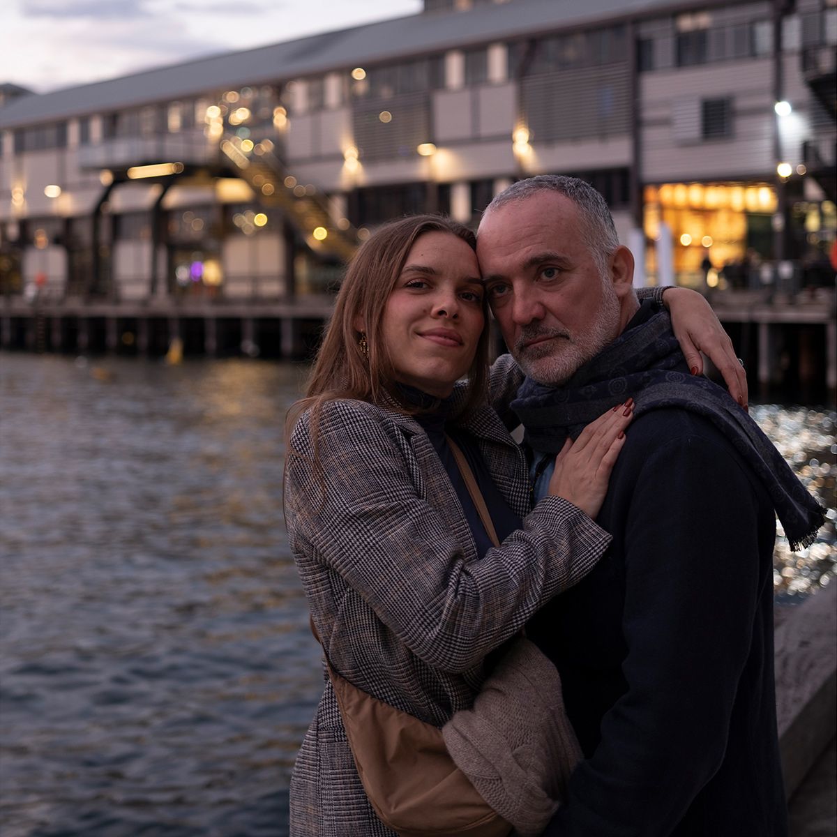 Colour twilight photo of couple embracing beside the water at Sydney Wharf. Photo by Raymond Mather.