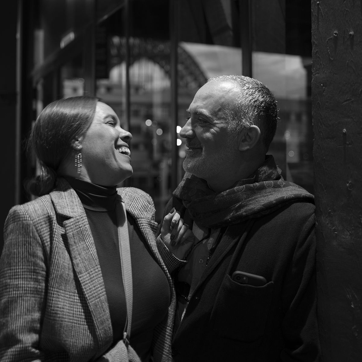 Four black and white photos showing people laughing and sharing joyful moments together in casual settings.